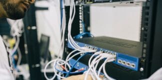 Informatyk podłącza kable Ethernet w domowej szafie serwerowej