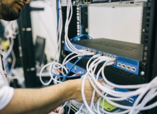 Informatyk podłącza kable Ethernet w domowej szafie serwerowej