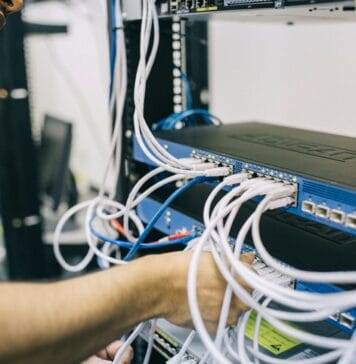 Informatyk podłącza kable Ethernet w domowej szafie serwerowej