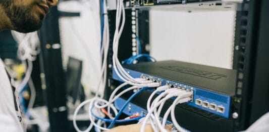 Informatyk podłącza kable Ethernet w domowej szafie serwerowej