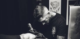Tatuażysta w skupieniu wykonuje tatuaż w studiu, zdjęcie czarno-białe