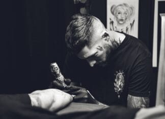 Tatuażysta w skupieniu wykonuje tatuaż w studiu, zdjęcie czarno-białe