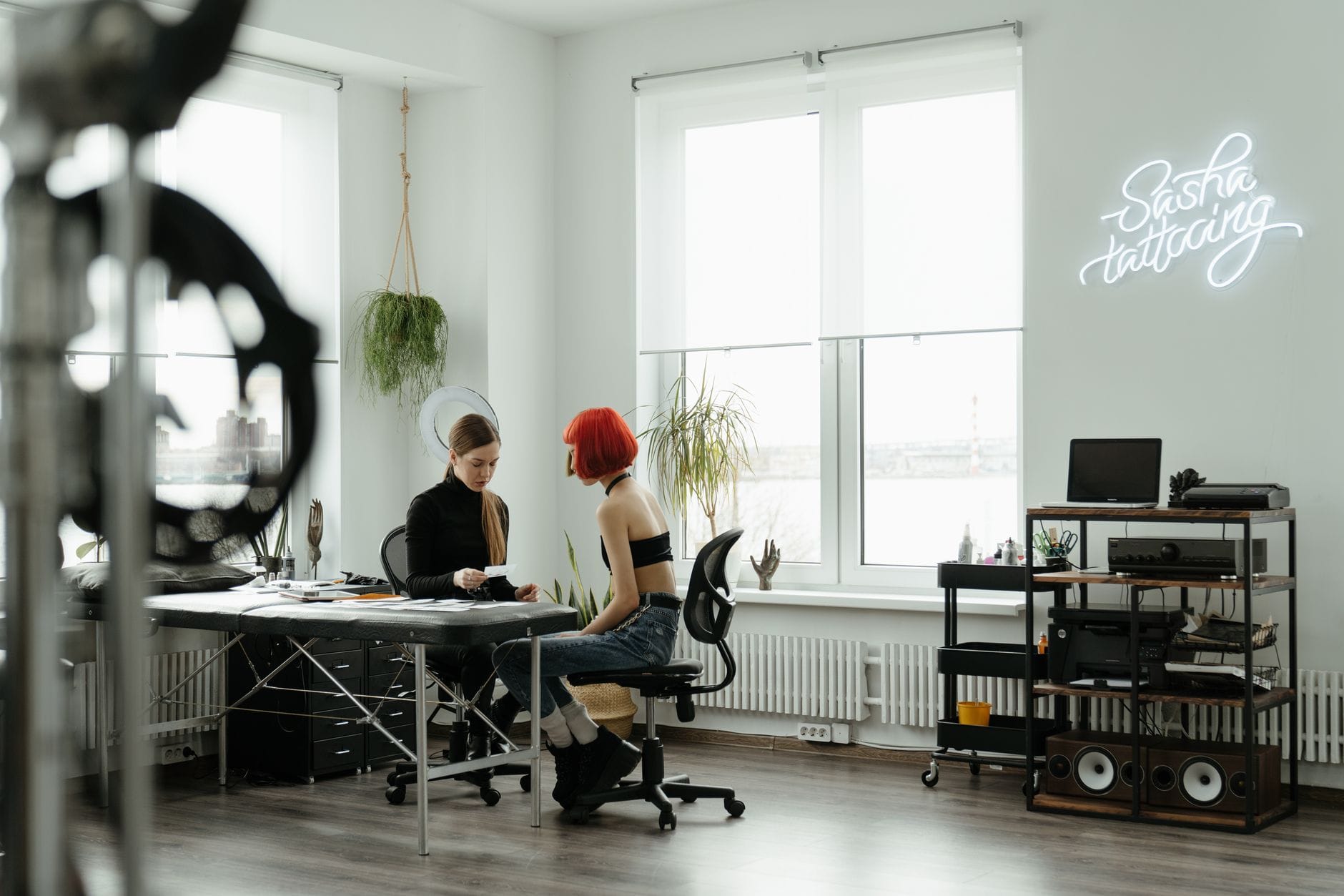 Dwie kobiety omawiają tatuaż w nowoczesnym, jasno oświetlonym studiu