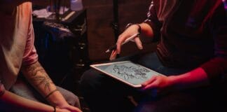 Tatuażysta omawia z klientem wzór smoka w studio tatuażu